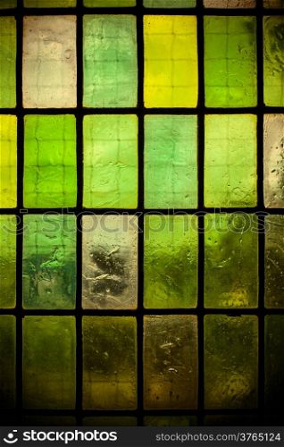 multicolored stained glass window with regular block pattern in hue of green
