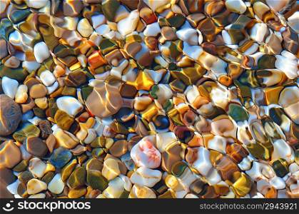 Multicolored stones in the clear sea water. Abstract background.