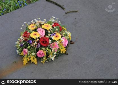 Multicolored sympathy flowers on a grey tombstone