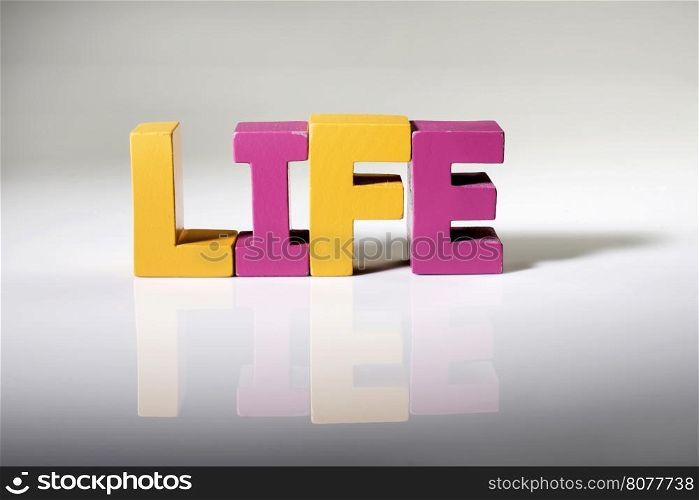 Multicolored text life made of wood. White background