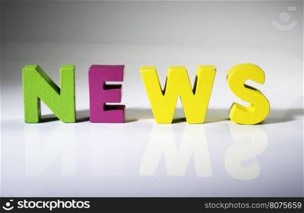 Multicolored text news made of wood. White background