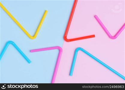 Multicolored vibrant plastic drinking coocktail straws on pink and blue trendy pastel background creative flat lay