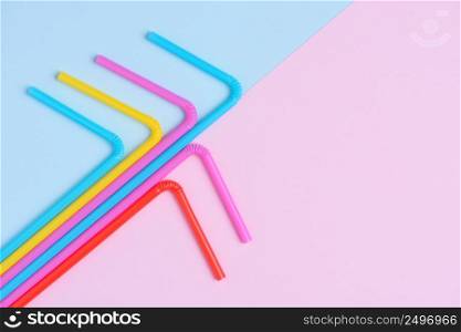 Multicolored vibrant plastic drinking coocktail straws on pink and blue trendy pastel background creative flat lay