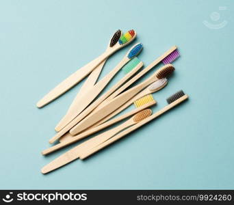 multicolored wooden toothbrushes on a blue background, plastic rejection concept, zero waste, top view