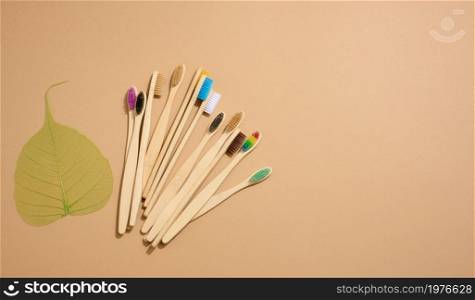 multicolored wooden toothbrushes on a brown background, plastic rejection concept, zero waste, top view
