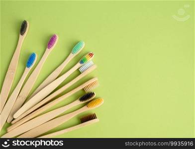 multicolored wooden toothbrushes on a green background, plastic rejection concept, zero waste, top view
