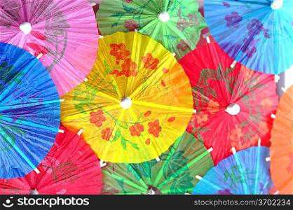 Multicoloured cocktail umbrellas on surface