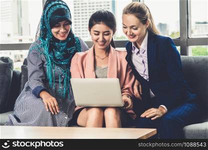 Multicultural working group. Team of businesswomen of different ethnicity, Caucasian, Asian and Arabic working together with laptop computer at office workplace. Multiethnic teamwork concept.