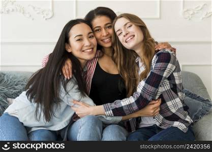 multiethnic best girlfriends hugging sitting sofa