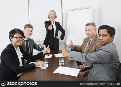 Multiethnic business people giving thumbs up in meeting