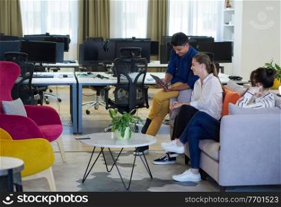 multiethnic business people Indian man with a female colleague working together on tablet computer in relaxation area of modern startup office