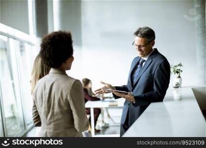 Multiethnic business people using digital tablet while standing in the modern office