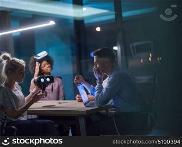 Multiethnic Business team using virtual reality headset in night office meeting Developers meeting with virtual reality simulator around table in creative office.