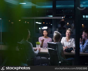 Multiethnic Business team using virtual reality headset in night office meeting Developers meeting with virtual reality simulator around table in creative office.