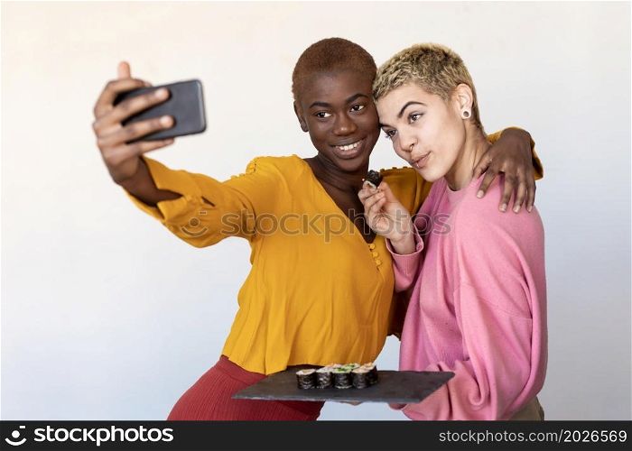 Multiethnic couple taking a selfie while having dinner. Multiethnic female friends taking a selfie while having dinner
