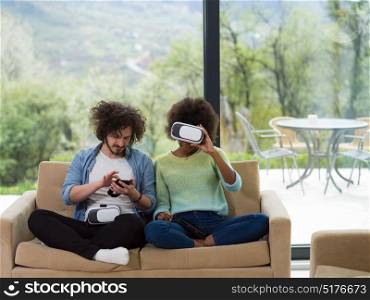 Multiethnic Couple using virtual reality headset in living room at home people playing game with new trends technology