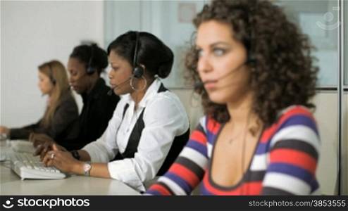 Multiethnic group of female customer service representatives talking on the phone and happy manager