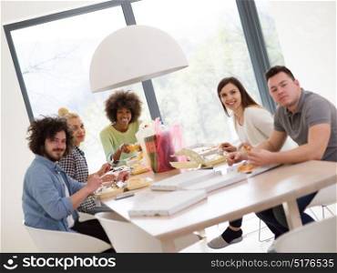 multiethnic group of happy friends spending time together with food and soda drinks, eating at home concept