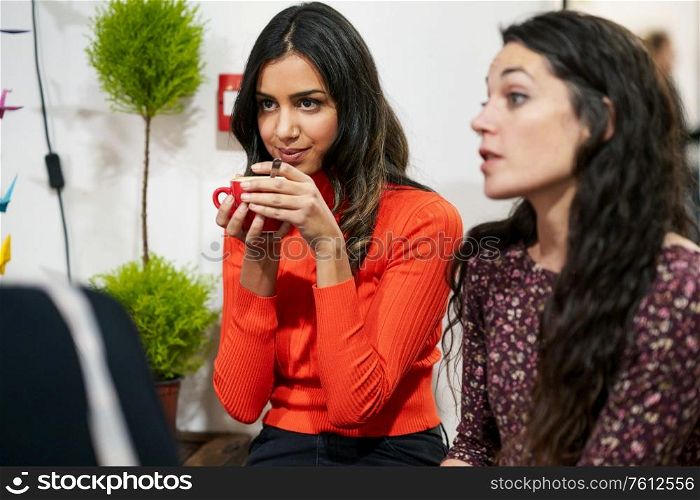 Multiethnic group of three happy female friends drinking coffee in a cafe bar.. Group of three happy friends drinking coffee in a cafe bar.
