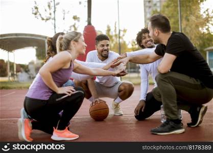 Multiethnic group of young basketball players resting on court together