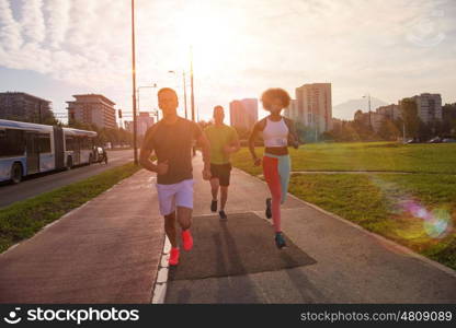 multiethnic group of young people on the jogging beautiful morning as the sun rises in the streets of the city