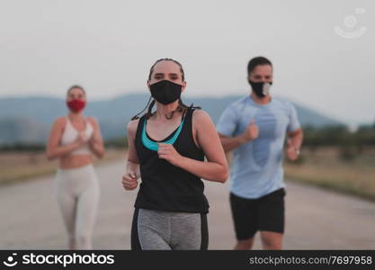Multiethnic runners group wear face masks running keep social distance outdoor. Fit healthy diverse team wears sportswear jogging in the evening on nature sports track distancing for safety.. Multiethnic runners group wear face masks running keep social distance outdoor. Fit healthy diverse team wears sportswear jogging in evening on nature sports track distancing for safety.
