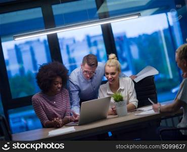 Multiethnic startup business team on meeting in modern night office interior brainstorming, working on laptop