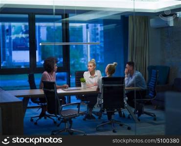 Multiethnic startup business team on meeting in modern night office interior brainstorming, working on laptop