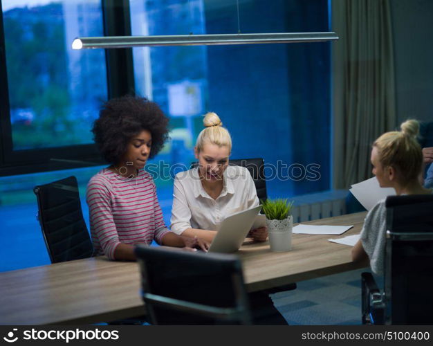 Multiethnic startup business team on meeting in modern night office interior brainstorming, working on laptop