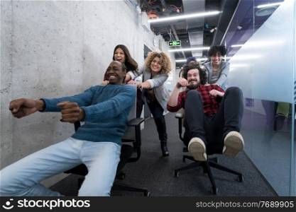 multiethnics startup business team of software developers having fun while racing on office chairs,excited diverse employees laughing enjoying funny activity at work break, creative friendly workers playing game together