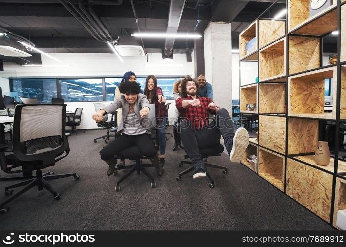 multiethnics startup business team of software developers having fun while racing on office chairs,excited diverse employees laughing enjoying funny activity at work break, creative friendly workers playing game together