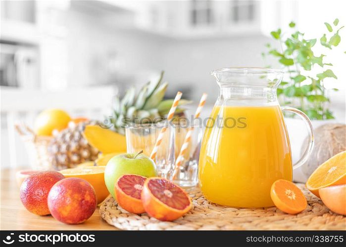 Multifruit juice and fresh fruit on table on kitchen background closeup