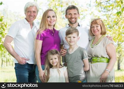 Multigeneration family portrait outdoors. Happy parents with two children and grandparents in summer park. Multigeneration family portrait