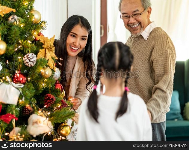Multigenerational asian Family decorating a Christmas tree. Mom daughter girl and grandfather decorate the Christmas tree prepare for season greeting of Merry Christmas and Happy Holidays.