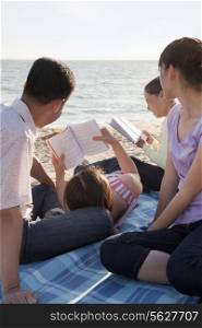 Multigenerational family relaxing and reading on the beach