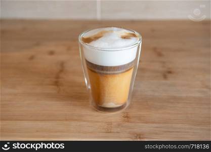 multilayer coffee or cappuccino in a glass cup on wooden table.. multilayer coffee or cappuccino in a glass cup on wooden table