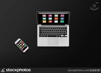 multimedia and technology concept - laptop computer with menu icons and smartphone top view. laptop computer with menu icons and smartphone