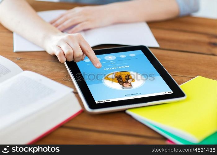 multimedia, education, technology and internet concept - close up of student woman with music player on tablet pc computer and notebook at home