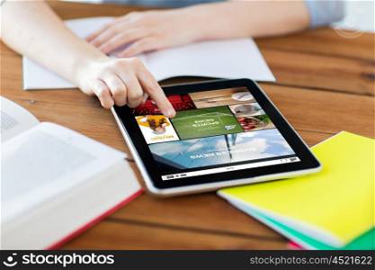 multimedia, education, technology and internet concept - close up of student woman with internet news application on tablet pc computer screen and notebook at home