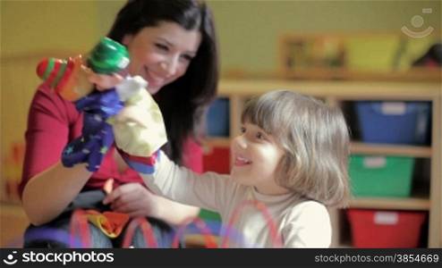 multiple shots of 2-3 years old girl and her teacher playing with marionette in kindergarten.