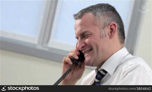 multiple shots of mid adult businessman talking on the phone in office