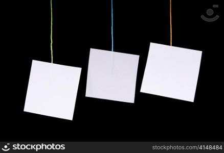 Multiple white paper tags hang on colorful string over black