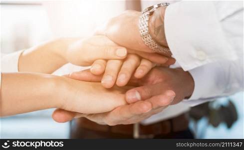 multiracial businesspeople stacking hands each other