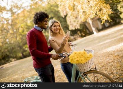 Multiracial couple with bicycle standing in the autumn park