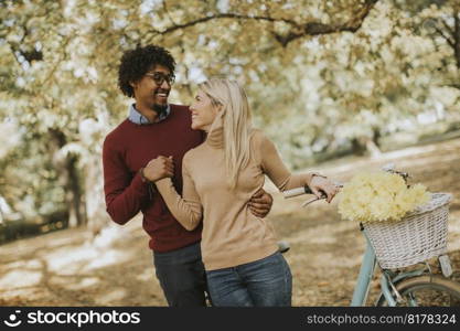 Multiracial couple with bicycle standing in the autumn park