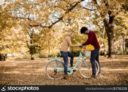 Multiracial couple with bicycle standing in the autumn park