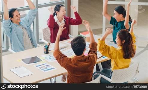 Multiracial group of young creative people in smart casual wear discussing business gesture hand high five, laughing and smiling together in brainstorm meeting at office. Coworker teamwork concept.
