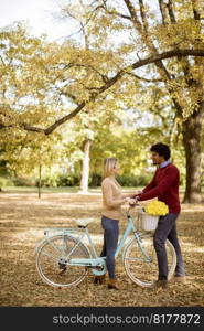 Multiracial young couple with bicycle standing in the autumn park