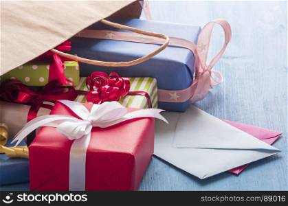 Multitude of colorful gift boxes and two envelopes coming out from a paper bag