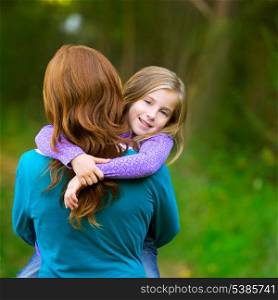 Mum holding daughter kid girl in her arms rear view smiling in outdoor